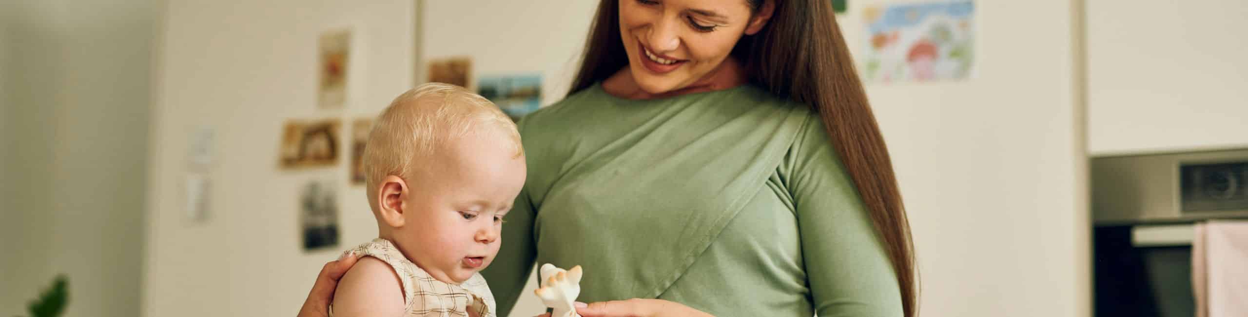 Mamica z dojenčkom v kuhinji se igra s priljubljeno žirafo – brezskrbni trenutki brez skrbi glede alergij