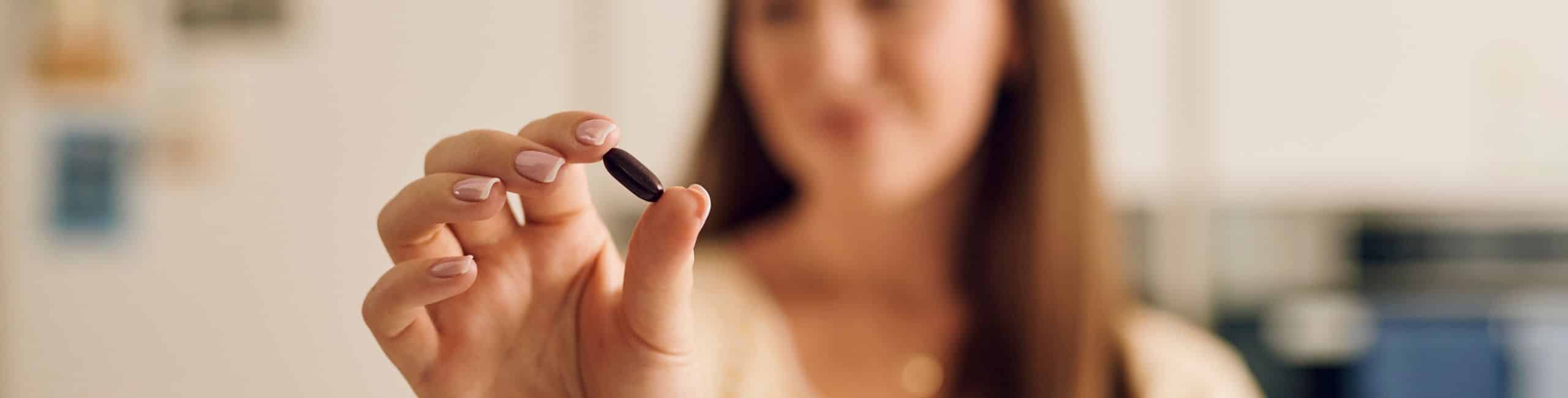 Ženska drži kapsulo Novalac prenatal z železom Lipofer mikrokapsule