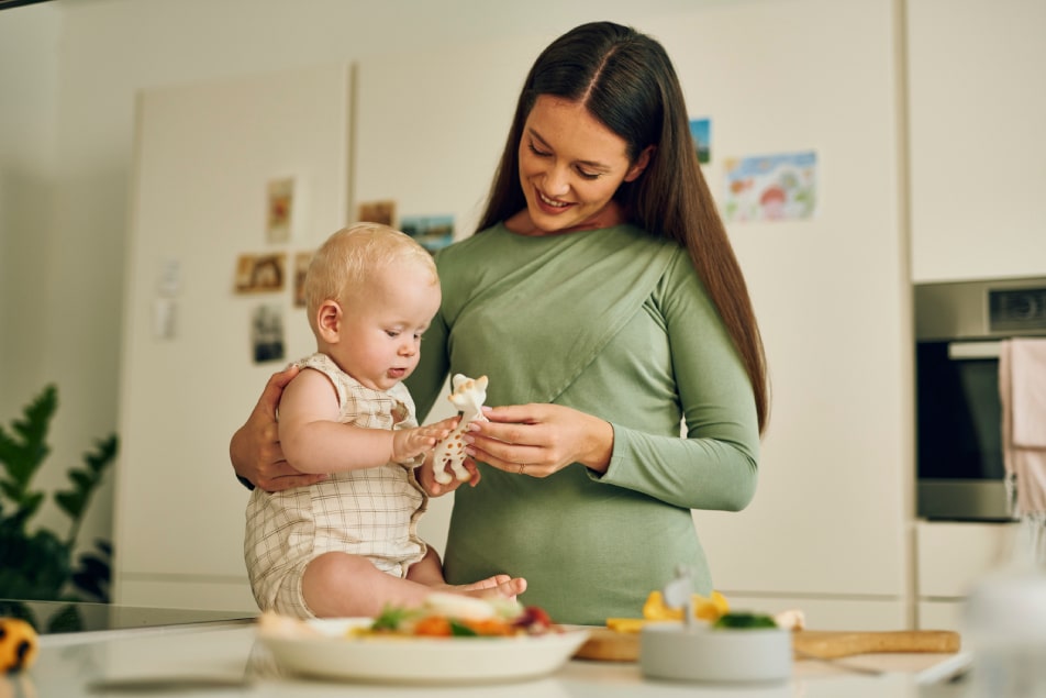 Mama in dojenček se igrata z žirafo med obrokom