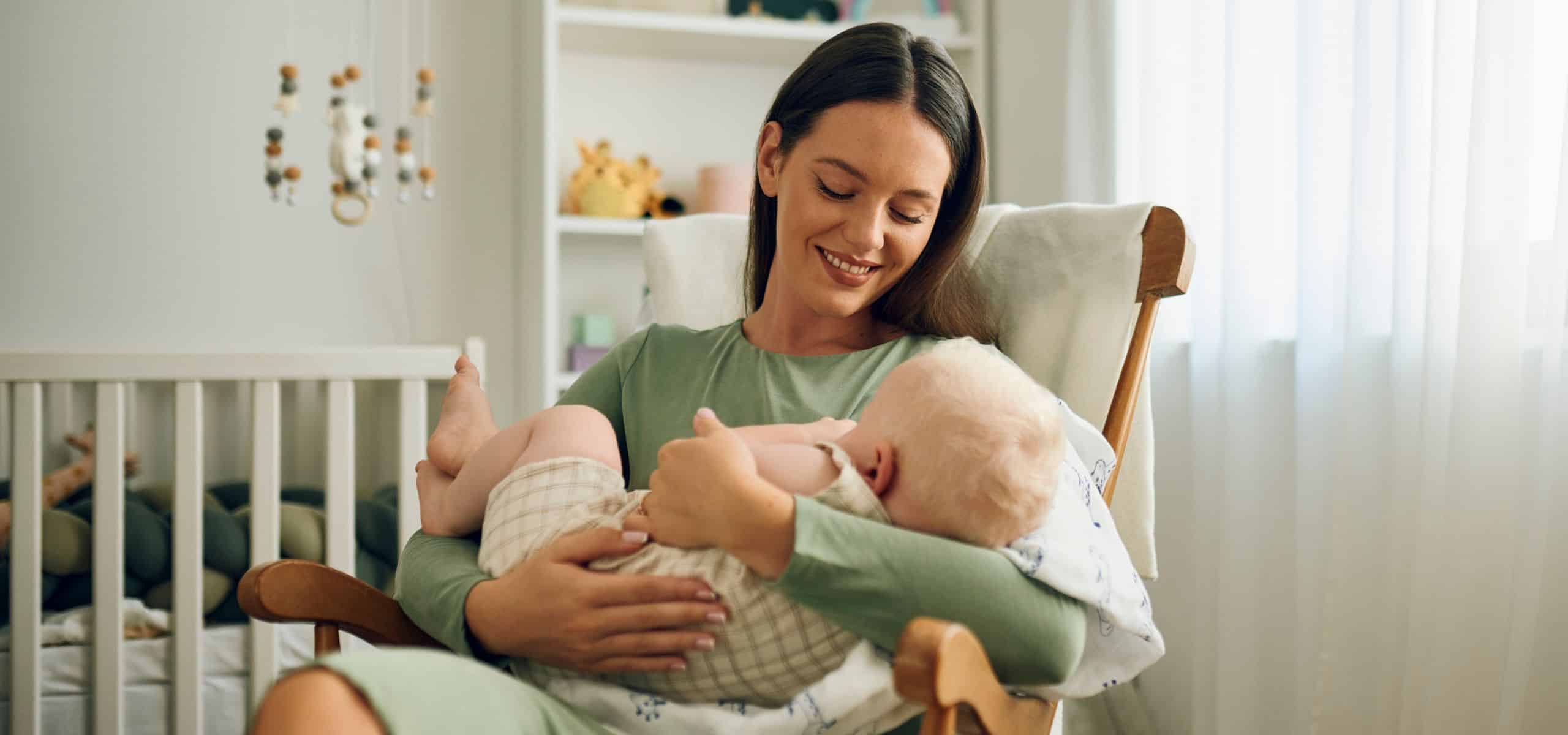 mamica drži dojenčka v naročju, pripravlja se na dojenje, čas po porodu